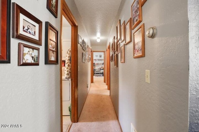 hall featuring light carpet and a textured ceiling