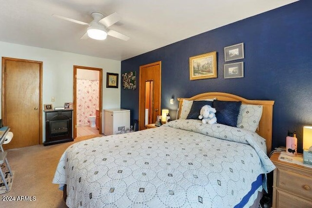 bedroom with ceiling fan, light colored carpet, and connected bathroom