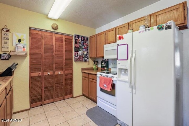 kitchen with white appliances, a textured ceiling, and light tile patterned floors