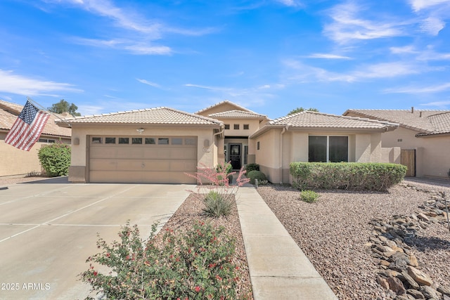view of front of home featuring an attached garage, stucco siding, a tiled roof, and driveway