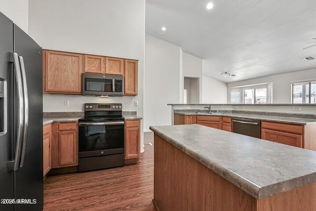 kitchen featuring sink, a kitchen island, kitchen peninsula, dark wood-type flooring, and stainless steel appliances