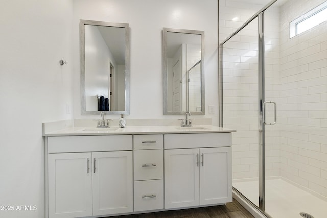 bathroom with double vanity, a stall shower, and a sink