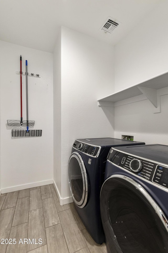 laundry area featuring washer and clothes dryer, laundry area, visible vents, wood tiled floor, and baseboards