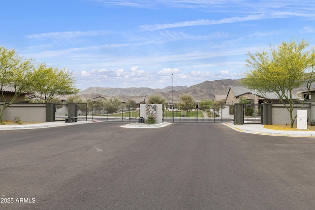 view of street with a gate, sidewalks, a gated entry, and a mountain view
