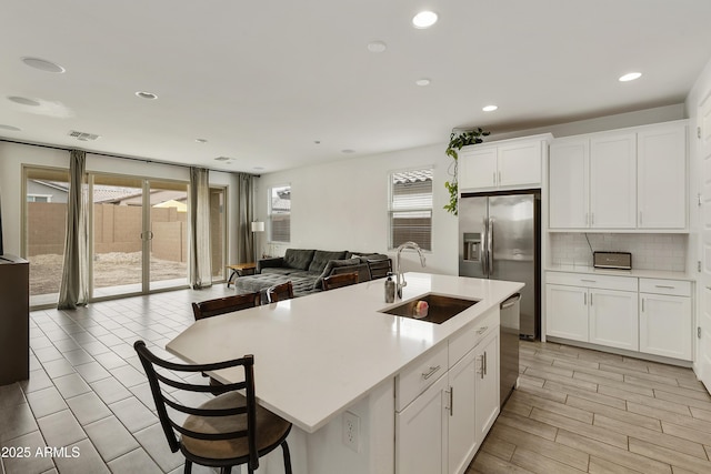 kitchen featuring a sink, stainless steel appliances, visible vents, open floor plan, and light countertops