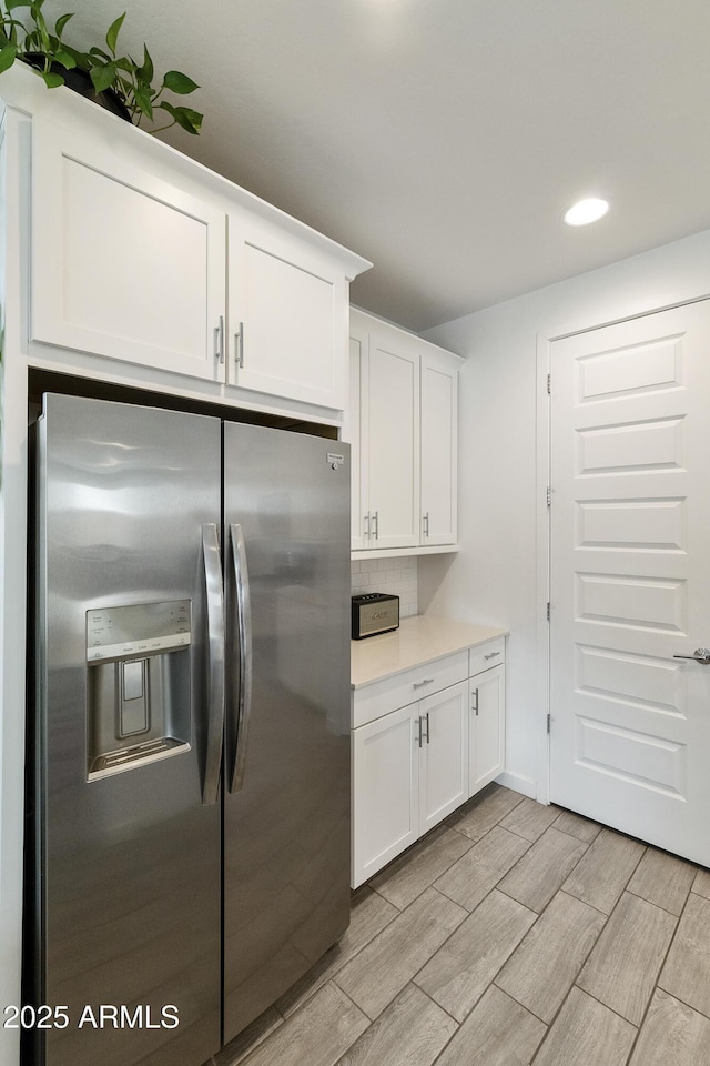 kitchen featuring white cabinetry, wood tiled floor, stainless steel fridge with ice dispenser, and light countertops
