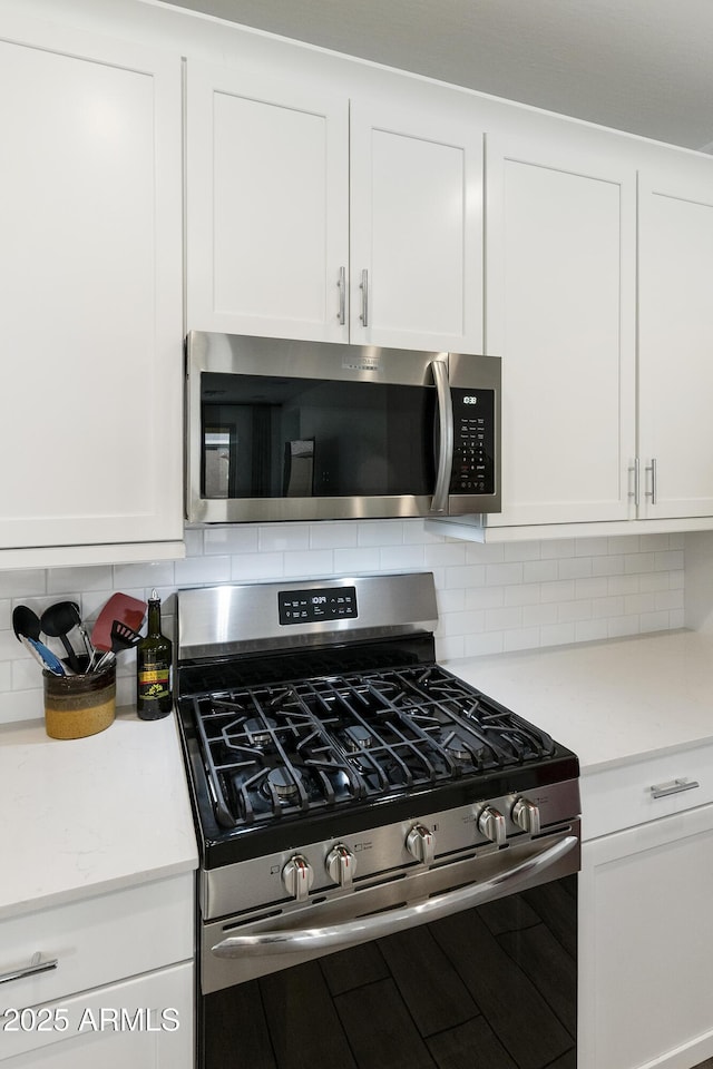 kitchen featuring white cabinets, light countertops, stainless steel appliances, and tasteful backsplash