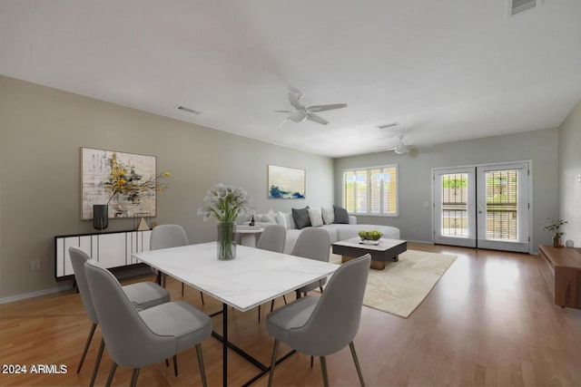 dining room with light wood finished floors, baseboards, visible vents, and ceiling fan