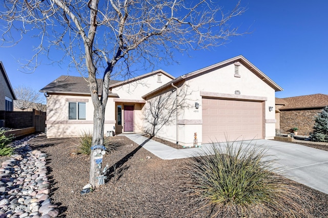 ranch-style home with driveway, an attached garage, fence, and stucco siding