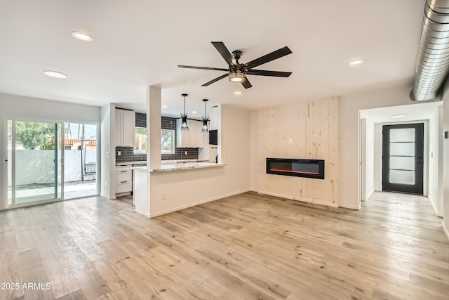 unfurnished living room featuring ceiling fan, a fireplace, and light hardwood / wood-style flooring