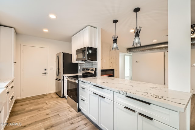 kitchen with white cabinetry, stainless steel appliances, light stone counters, decorative backsplash, and kitchen peninsula