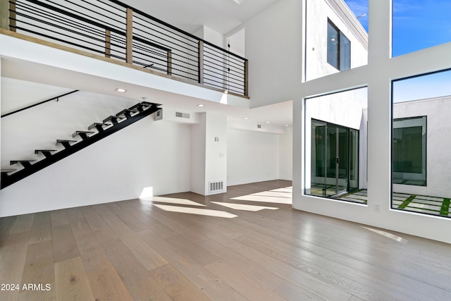 unfurnished living room featuring a high ceiling and hardwood / wood-style floors