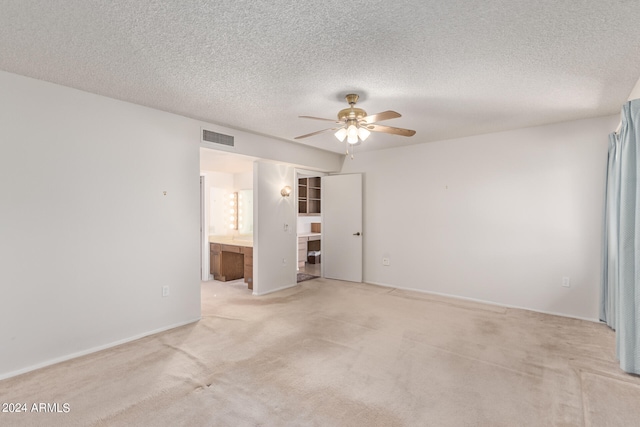 carpeted spare room featuring a textured ceiling and ceiling fan