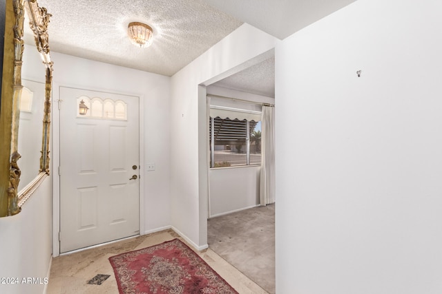 entrance foyer with a textured ceiling and light colored carpet