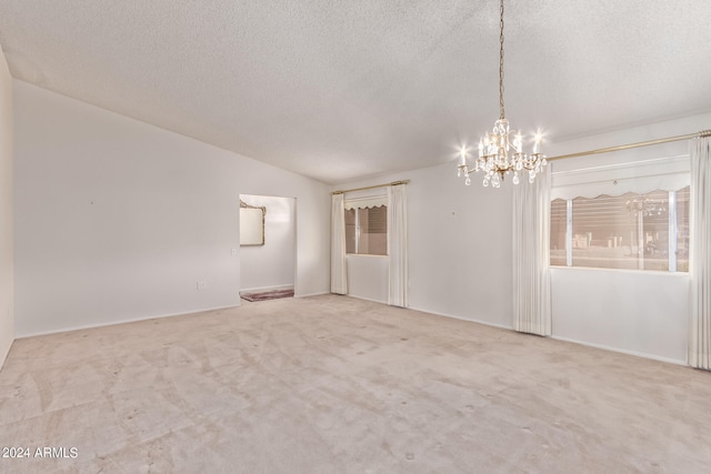 empty room featuring a textured ceiling, lofted ceiling, and light colored carpet