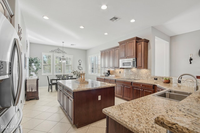 kitchen with sink, hanging light fixtures, a kitchen island, stainless steel fridge, and black electric stovetop