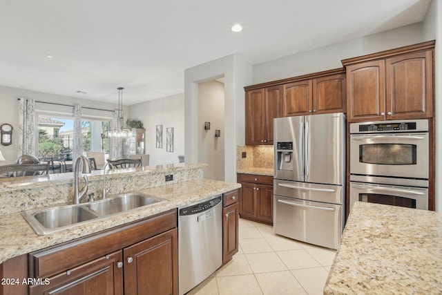 kitchen with hanging light fixtures, sink, tasteful backsplash, light tile patterned floors, and appliances with stainless steel finishes