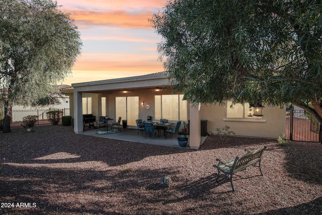 back house at dusk with a patio area