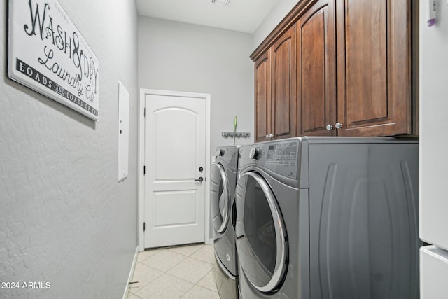 clothes washing area with light tile patterned floors, cabinets, and washer and dryer