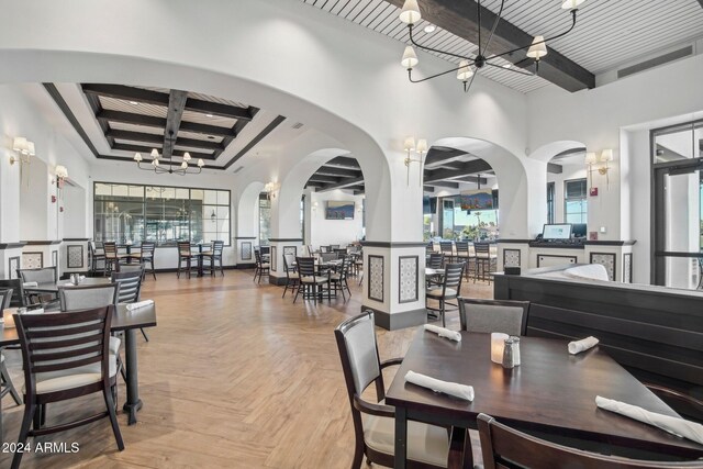 dining area featuring light parquet flooring, beamed ceiling, and an inviting chandelier