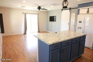 kitchen featuring a barn door, a center island, dark wood-type flooring, white refrigerator with ice dispenser, and blue cabinets