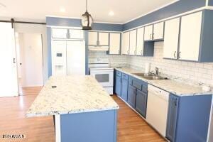 kitchen with decorative light fixtures, a center island, sink, white appliances, and blue cabinetry