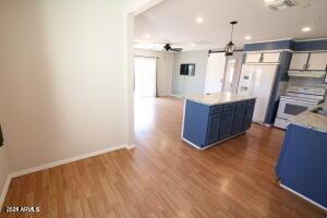 kitchen with a barn door, ceiling fan, blue cabinetry, stove, and wood-type flooring