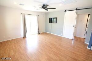 unfurnished room featuring ceiling fan, a barn door, and light hardwood / wood-style flooring