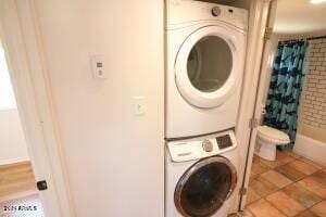 clothes washing area featuring stacked washing maching and dryer