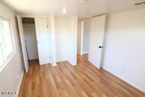 unfurnished bedroom with light wood-type flooring and a closet