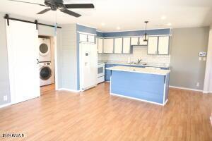 kitchen with stacked washer / dryer, pendant lighting, white fridge, backsplash, and a barn door