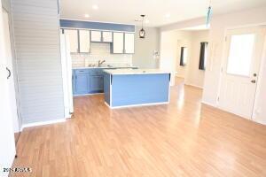 kitchen with backsplash, pendant lighting, light hardwood / wood-style flooring, and sink