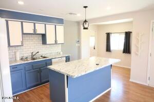 kitchen featuring a center island, decorative light fixtures, white cabinetry, sink, and blue cabinets