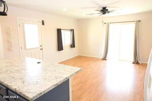 kitchen featuring ceiling fan, light stone countertops, light hardwood / wood-style flooring, and a healthy amount of sunlight