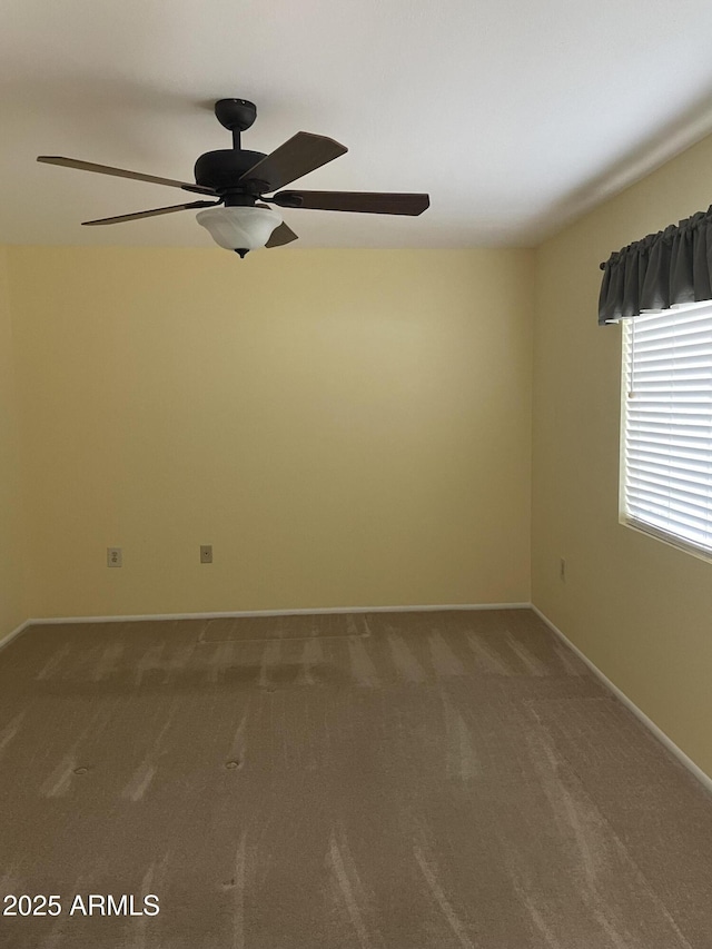 carpeted empty room with baseboards and a ceiling fan