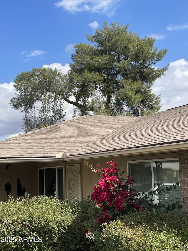 view of side of home with roof with shingles