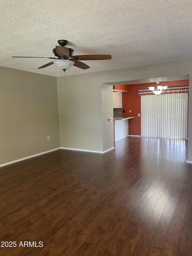 unfurnished room with baseboards, a textured ceiling, dark wood finished floors, and ceiling fan with notable chandelier