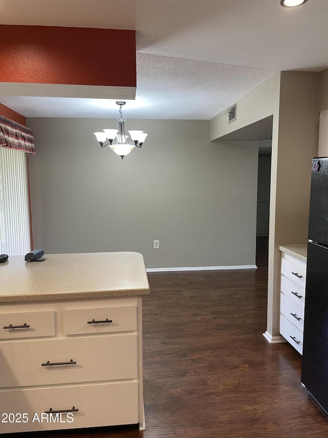 kitchen with light countertops, white cabinets, freestanding refrigerator, and a textured ceiling