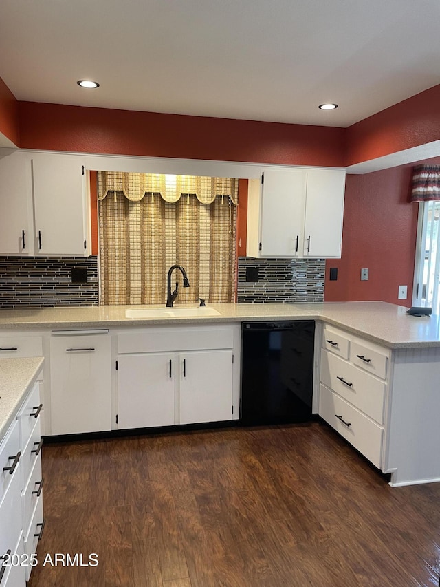 kitchen featuring dark wood finished floors, a peninsula, black dishwasher, and a sink