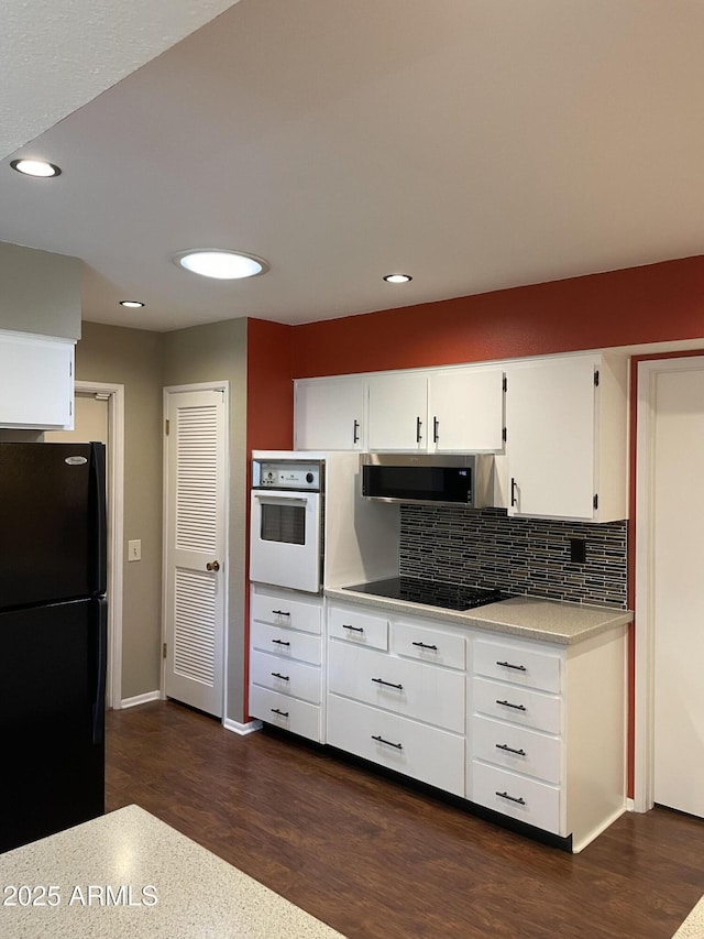 kitchen featuring dark wood finished floors, black appliances, light countertops, and tasteful backsplash