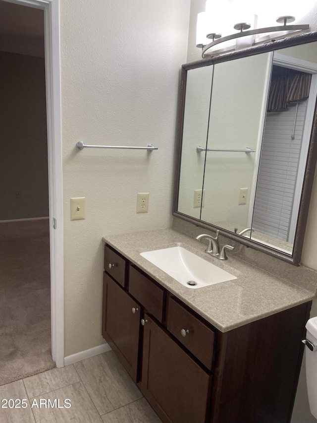 bathroom with toilet, vanity, and baseboards