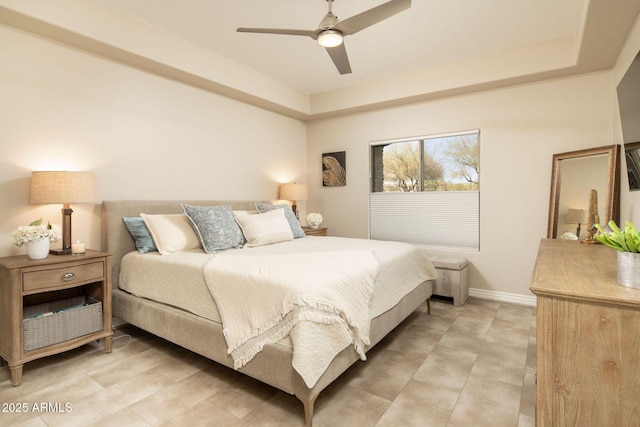 bedroom with a ceiling fan, a raised ceiling, and baseboards