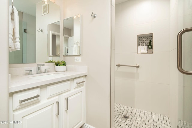full bathroom featuring vanity, a shower stall, and visible vents
