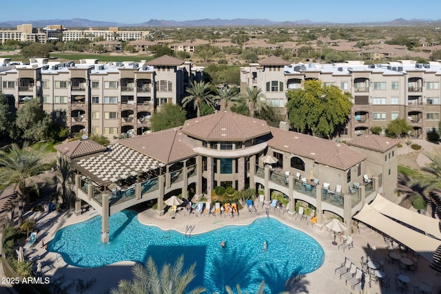 pool with a patio area, a mountain view, and a residential view