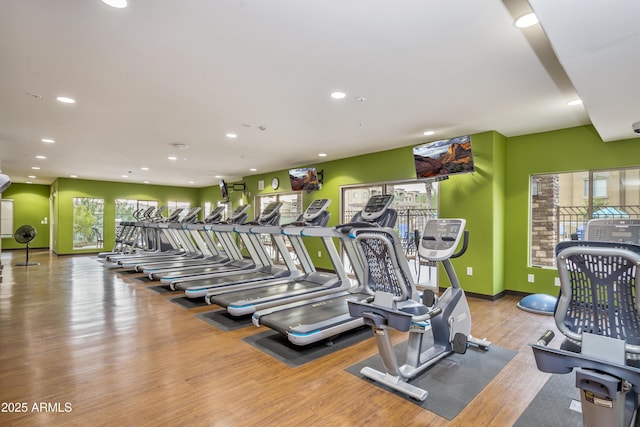 exercise room featuring recessed lighting, a healthy amount of sunlight, baseboards, and wood finished floors