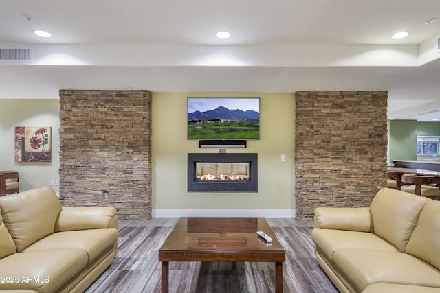 living room with visible vents, baseboards, a lit fireplace, and wood finished floors