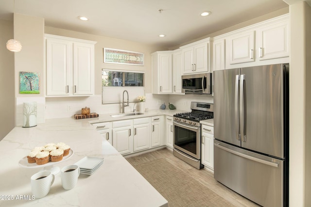 kitchen with light stone countertops, recessed lighting, a sink, white cabinets, and appliances with stainless steel finishes