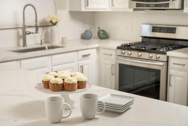 kitchen featuring white cabinetry, light countertops, stainless steel range with gas stovetop, and a sink