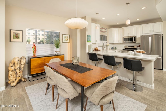 dining area with recessed lighting, light wood-style flooring, and baseboards