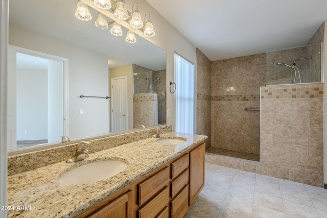 bathroom featuring tile patterned flooring, vanity, and a tile shower